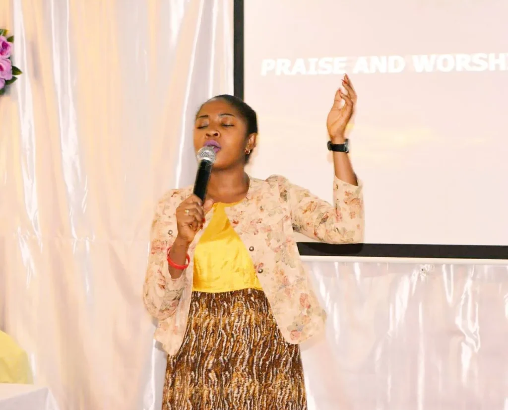 Vanessa Musenja singing in worship with a hand raised